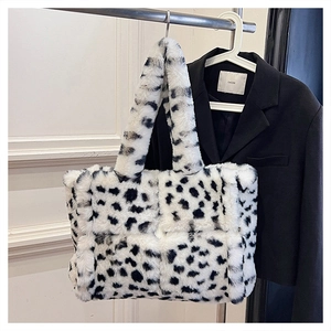 Detail of checkered faux fur tote bag with cow print pattern on a silver hanger