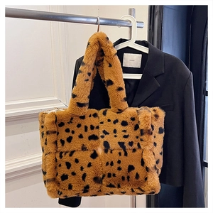 Close-up of leopard print plush tote bag with thick faux fur handles on a hanger
