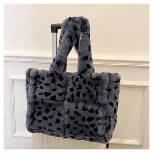 Detail of gray cow print faux fur tote bag hanging on a white suitcase handle