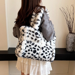 Women's fluffy cow print plush tote bag shown on model in minimalist interior setting