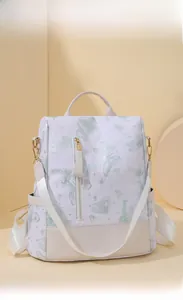 Close-up of butterfly print backpack with golden hardware on a soft beige background