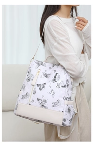 Detail of white butterfly print backpack with beige leather trim worn by a model