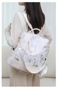 Detail view of butterfly print backpack with side zipper pocket and beige leather base