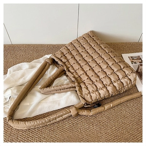 Détail du sac fourre-tout matelassé kaki avec poignées à nœuds sur un tapis tressé