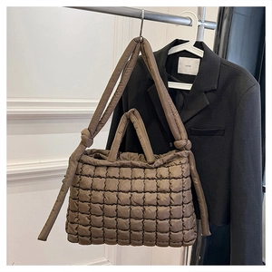 Détail d'un sac cabas matelassé marron foncé avec texture gonflée et bandoulière à nœud