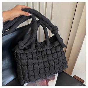 Détail d'un sac cabas matelassé noir avec une bandoulière à nœud au design unique