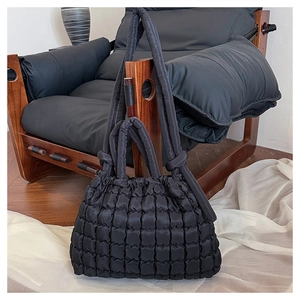 Détail du sac cabas matelassé noir avec texture à bulles sur une chaise vintage