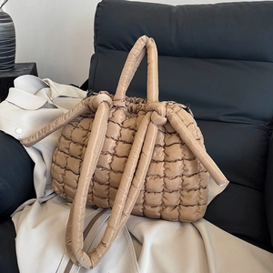 Sac fourre-tout matelassé kaki avec poignées rondes et bandoulière sur un canapé