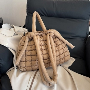 Sac fourre-tout matelassé kaki avec bandoulières rembourrées sur un siège en cuir avec trench