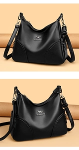 Detail of black litchi grain leather texture and metallic kangaroo logo on a handbag