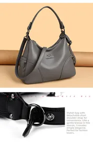 Detail view of the detachable shoulder strap with metal buckles on a grey leather handbag