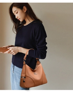 Detail of caramel brown hobo bag showing litchi texture and metal kangaroo logo emblem