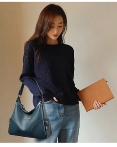 Close-up of deep teal leather handbag featuring silver kangaroo logo and zipper accents