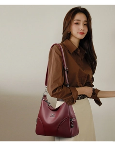 Detail of burgundy lychee-textured leather shoulder bag with metallic kangaroo logo