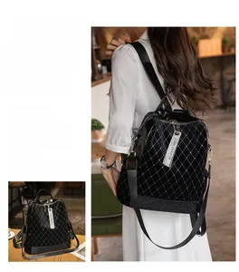 Detail of black quilted backpack with rivets and side zipper featuring branded pendant
