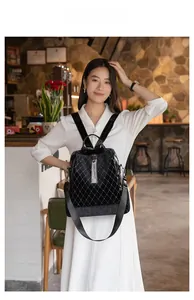 Close-up of black quilted backpack with silver studs and decorative strap in a cafe