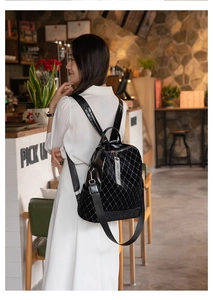 Detail of black quilted leather backpack with diamond studs and logo strap pendant