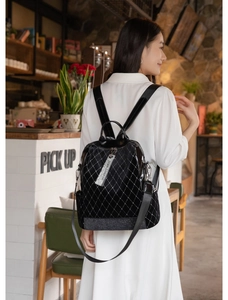 Detail of black rivet backpack with silver diamond pattern and brand tag in soft lighting