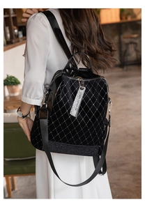 Detail of glossy black backpack with silver rivet quilted pattern and metallic zippers