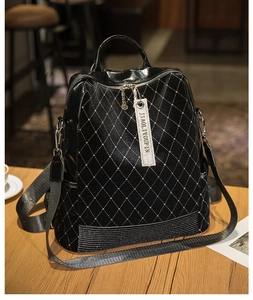Detail of black quilted leather backpack with sparkling rivet studs and zipper hardware