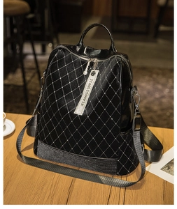 Close-up of black quilted leather backpack with silver studs and sparkling rhinestone base