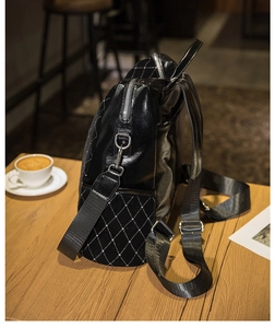 Detail of black quilted leather backpack with silver studs on a wooden cafe table