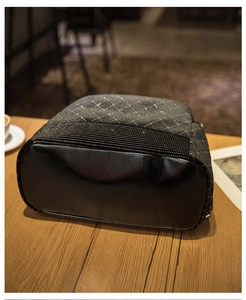 Detail of the black quilted backpack with luxury stud accents on a wooden table