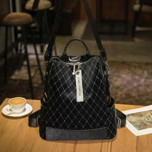 Fashionable black quilted backpack with rivets and studs on a cafe table setting