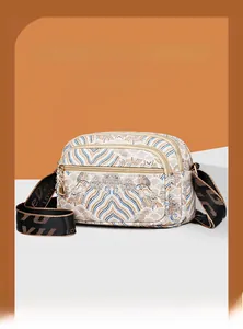 Close-up of vintage embroidered floral shoulder bag with wide strap and double zippers