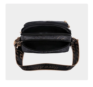 Macro detail of black paisley patterned crossbody bag showing three zipper compartments