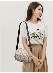 Detail of bohemian print crossbody bag with multiple zippers and wide strap shown on model