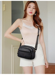 Detail shot of black vintage jacquard crossbody bag with multiple zippers and wide strap