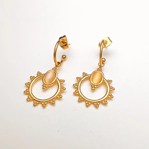 Detailed view of C-shaped 18K gold earrings with white opal sunburst charm pendants