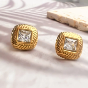 Boucles d'oreilles carrées plaquées or 18K avec zircon sur un fond en pierre