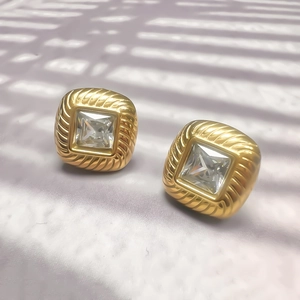 Détail des boucles d'oreilles carrées dorées avec zircons et texture de corde tressée