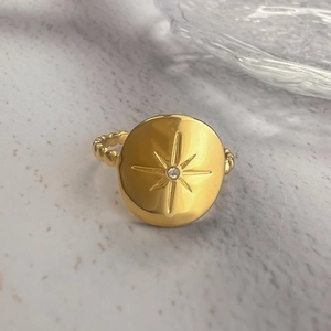 Gold stainless steel sunburst star ring with center zircon on marble surface