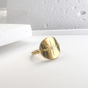 Gold eight-pointed star ring with zircon inlay and beaded band on white stone base