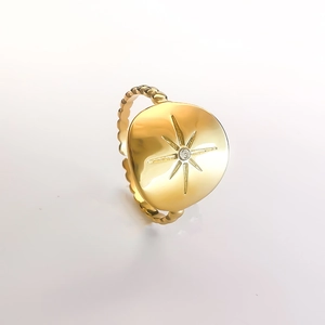 Macro detail of gold eight-pointed star ring with center crystal and beaded band
