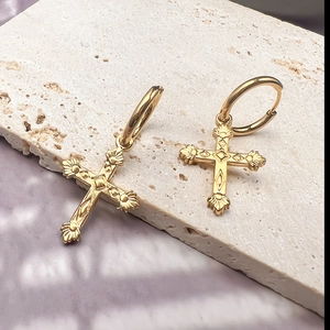 Detailaufnahme der goldenen Vintage-Kreuzanhänger mit feiner geometrischer Gravur auf Creolen