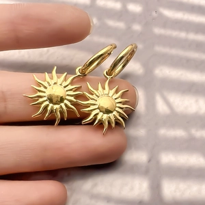 Nahaufnahme von goldenen Sonnenanhänger-Ohrringen aus Edelstahl mit 18K Vergoldung