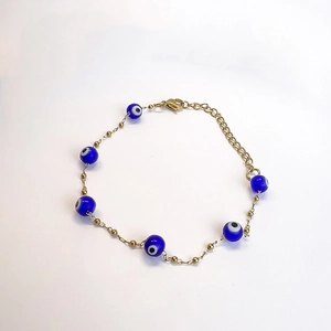 Détail macro du bracelet plaqué or 18K avec perles bleues œil de démon et fermoir mousqueton