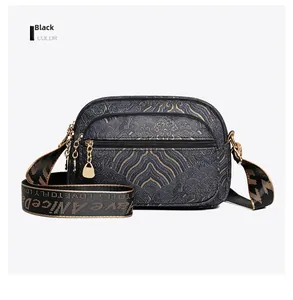 Detail of vintage black crossbody bag showing multiple zippers and golden cloud patterns