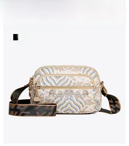 Front view of ethnic style woven crossbody bag with gold floral patterns and triple zippers