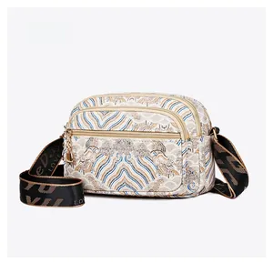 Detail view of multi-pocket crossbody bag with vintage ethnic print and gold zippers