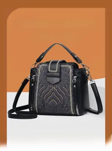 Close-up of vintage black leather handbag featuring golden ethnic pattern and metal zipper