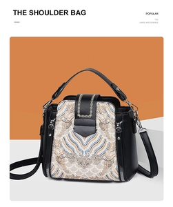 Detail of the chic embroidered front panel and metal buckle on the black shoulder bag
