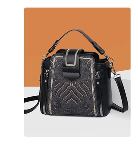 Close-up of black crossbody bag featuring gold wave embroidery and premium faux leather texture
