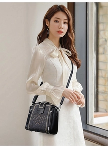 Detail of elegant black crossbody bag with golden embroidery and adjustable leather strap
