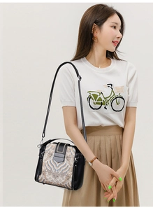 Detail shot of a black crossbody bag with traditional embroidery on a female model