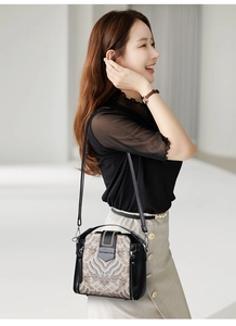 Detail of elegant ethnic embroidery on black leather crossbody bag with metal buckle